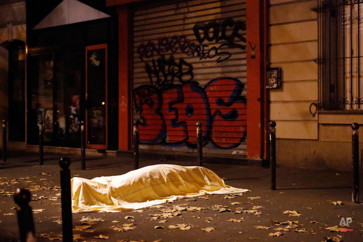 FOR USE AS DESIRED, YEAR END PHOTOS - FILE - A victim of a terrorist attack lays dead outside the Bataclan theater in Paris, Nov. 13, 2015. (AP Photo/Jerome Delay, File)